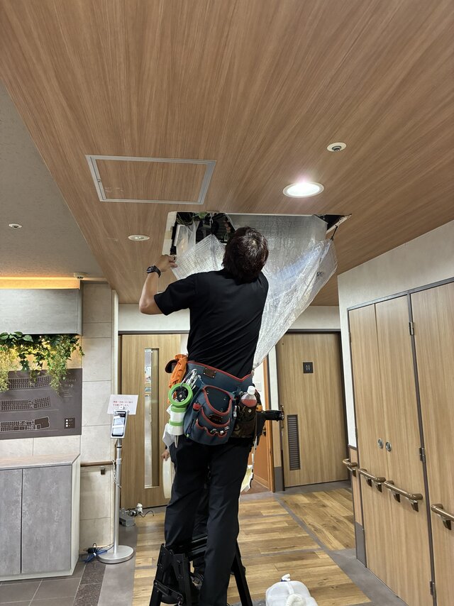 スーパーコート高石羽衣の共用部にて、業者が養生シートを使い天井埋込型エアコンを洗浄クリーニングしている様子