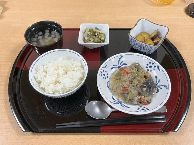 alt="スーパーコート高石羽衣で提供されたイベントランチ「からだに効く薬膳料理～夏のひえ・むくみ～」の配膳写真。ご飯、豚ひき肉と夏野菜の炒め物、さつま芋の甘煮、もずくとらっきょうの和え物、とうもろこしと冬瓜のスープが黒と赤のお盆にきれいに並べられている様子。"