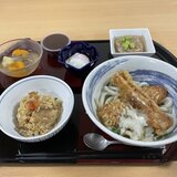 黒と赤のお盆に載ったスーパーコート高石羽衣の昼食「プライムメニュー」（五目御飯、ちくわ天がのった冷やしおろしうどん、温泉卵、蓮根はさみ蒸し、水ようかん、フルーツみつ豆）