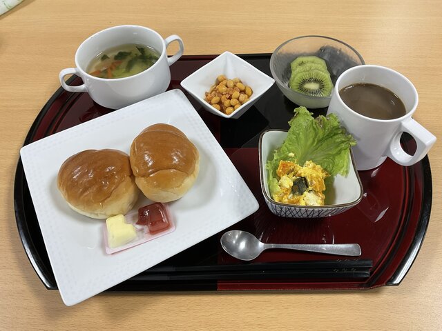 alt="スーパーコート高石羽衣の朝食プライムメニュー（ロールパン、大豆のトマト煮、南瓜のサラダ、コンソメスープ、キウイ、飲み物）"