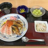 スーパーコート高石羽衣で提供されたごちそうメニュー。お盆の上に置かれた、鰻・海老・いくらが贅沢に乗った彩り豊かなちらし寿司、スパゲティサラダ、清汁、漬物、デザートのマスカット。