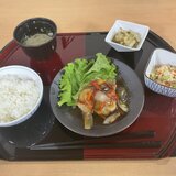 スーパーコート高石羽衣の夕食「プライムメニュー」の配膳写真。黒と赤のお盆の上に、メインの赤魚の甘酢あんかけ、ご飯、清汁、炒り豆腐、キャベツの塩昆布和えが綺麗に並んでいる。