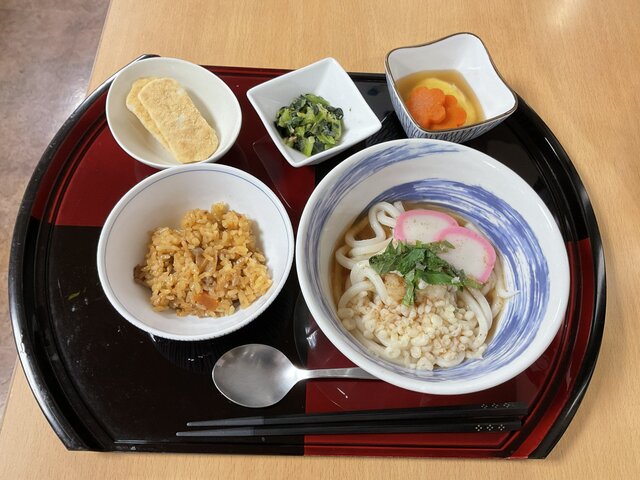 alt="スーパーコート高石羽衣の昼食プライムメニュー。梅かつおうどん、ミニ炊き込みご飯、ふんわり野菜の豆腐寄せ、青梗菜の和え物がトレーに並んだ食事"