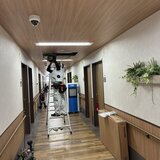 スーパーコート高石羽衣の2階廊下で脚立に登り天井埋込型エアコンの取り付け工事を行う作業員の様子