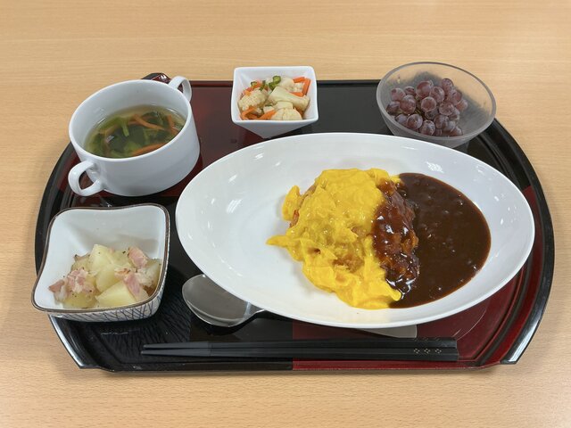 <img src="画像のURL" alt="スーパーコート高石羽衣の昼食。ふわとろ卵のオムライス、ジャーマンポテト、野菜サラダ、コンソメスープ、季節のフルーツが並んだお盆。">