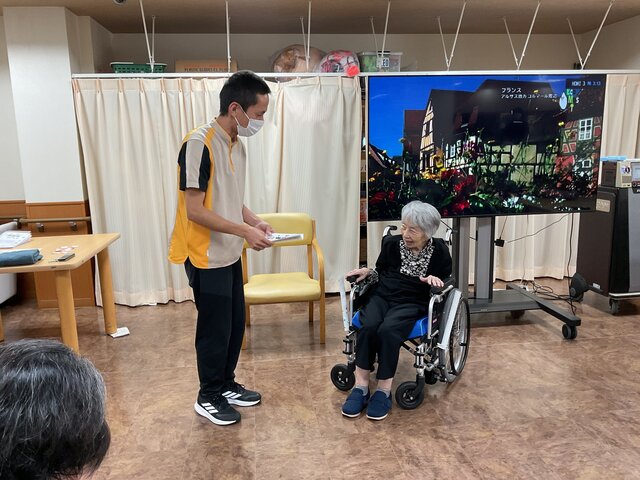 体操キャンペーン表彰式にて、スタッフから表彰状と記念品を受け取るご利用者様の様子