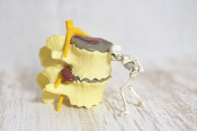 ベッドで腰を押さえる高齢者