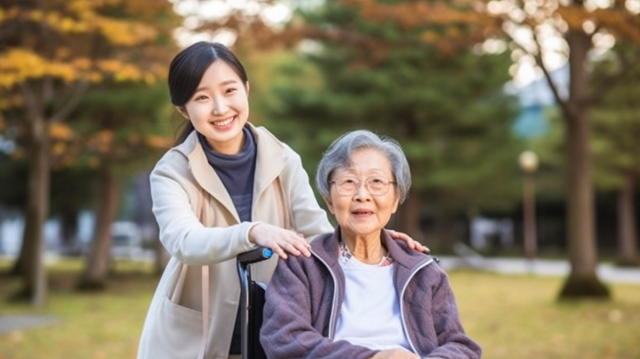 プランターの花に水をやる高齢女性