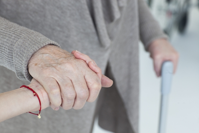 高齢女性の手を握る介護者